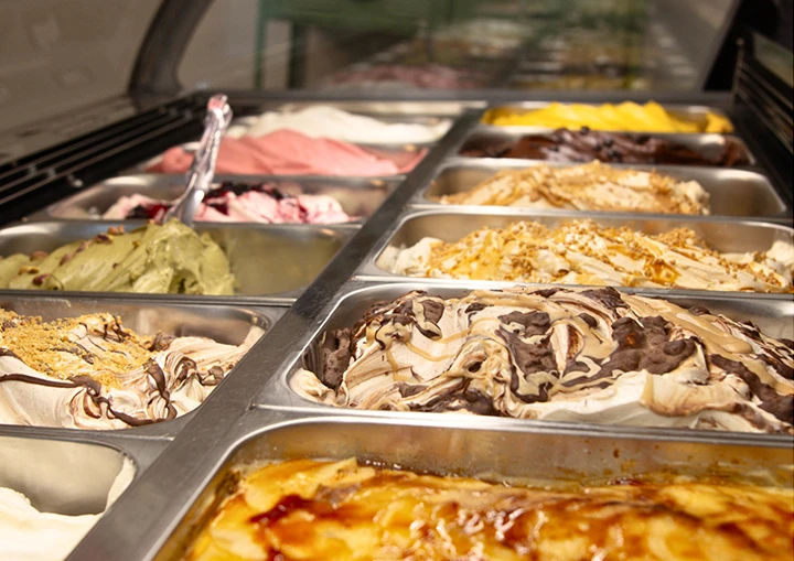 Imagen de una vitrina para helados artesanales con varias cubetas con diferentes tipos de helados y sabores